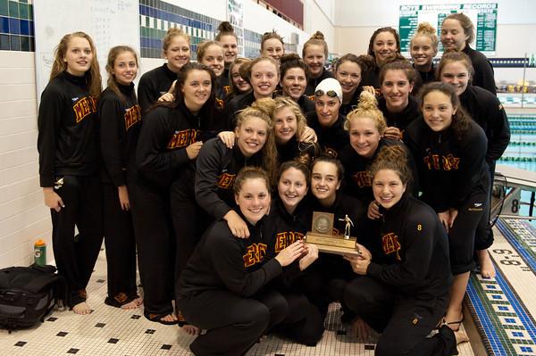 The Mercy swim team poses with their ninth consecutive Oakland County Champion trophy at Lake Orion high school.