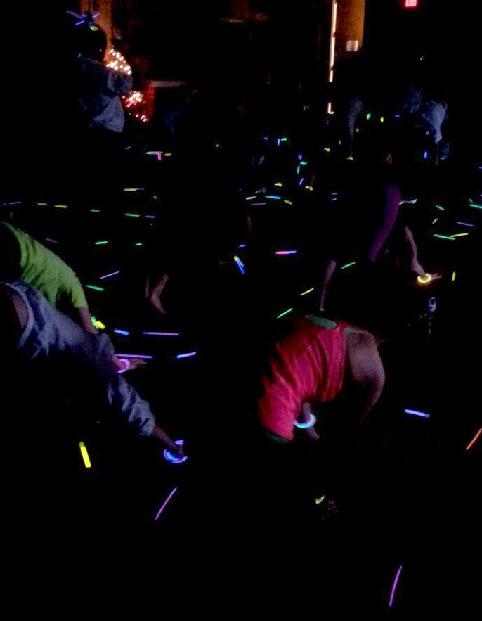 Caption: Freshmen bend and stretch in the downward-facing dog pose during Link Crews December Glowga event. 