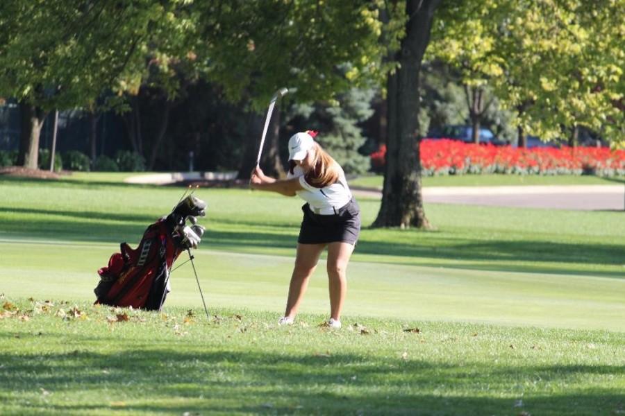 Caroline Bland strikes a ball out of the rough grass. Bland hopes to master this shot before Catholic Leagues. 
(Photo Credit: Kate Shaw)