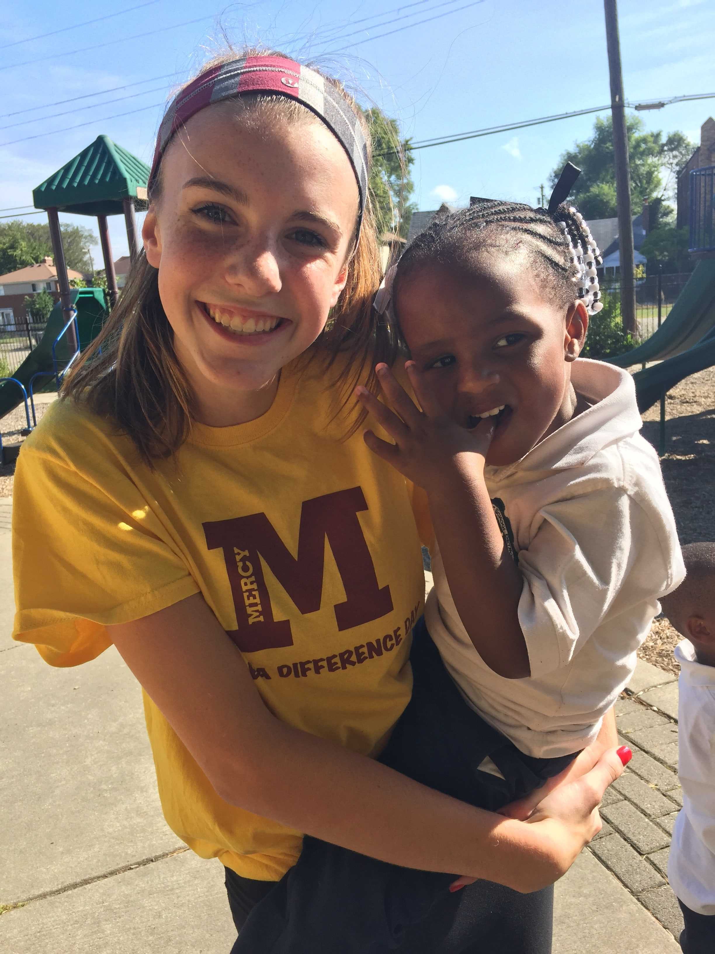 Mercy sophomore Maggie Belevie holds the Gesu student she spent her day with. According to Delevie, she and the young girl played tag and climbed the jungle gym. (Photo credit: Allia McDowell)