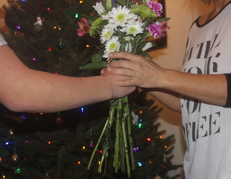 Hands unite as one family member passes off flowers to another. Gift-giving brings along emotions of joy, love, and unity — regardless of whether one is on the giving or receiving end. (Photo Credit: Brooklyn Rue)