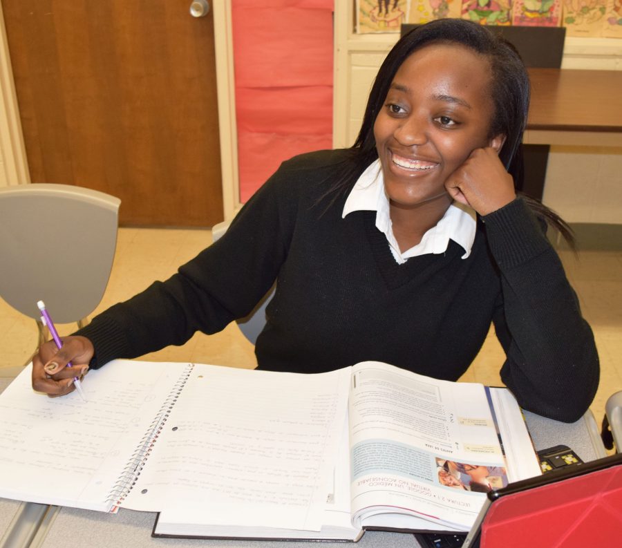 Senior Chiaka Ibe smiles as she works during her off time to complete homework. Ibe is determined to make her final semester at Mercy High School one to remember. (Photo Credit: Molly Lyons)