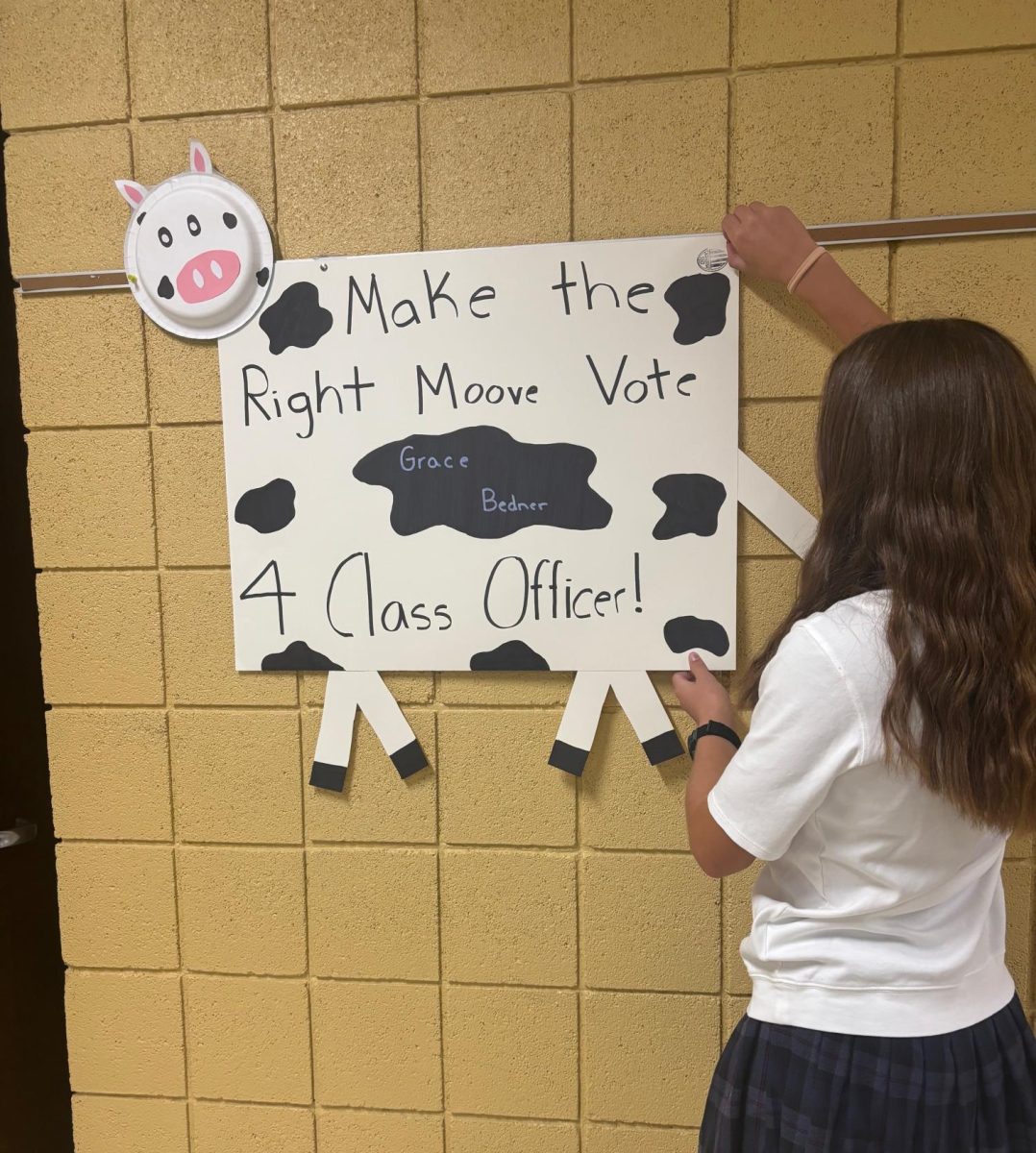 Freshman class officer candidate Grace Bedner hangs her campaign poster.